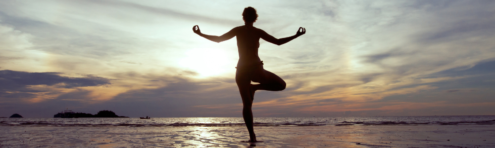 woman practicing yoga on the beach